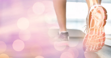 Composition of spots of light over woman running on treadmill with foot bones showing. exercise, active lifestyle and injury concept digitally generated image.の写真素材