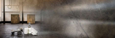 Composition of dumbbells, towel and water bottle on gym floor with blurred grey light. exercise, gym...