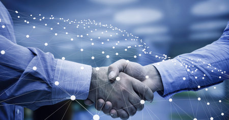 Network of connections over mid section of two businessmen shaking hands at office. global networking and business technology conceptの写真素材