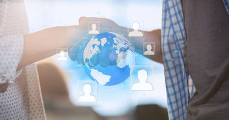 Network of profile icons over globe against mid section of two business people shaking hands. global...