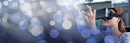 Blue sparkling transition over a woman using vr headset, virtual reality concept. digitally generated imageの写真素材