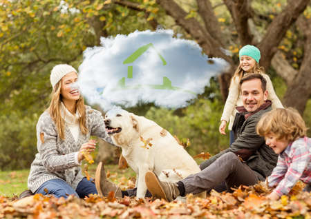 Composition of cloud with house icon over happy caucasian family with dog in autumn park. home and family life concept digitally generated image.の写真素材