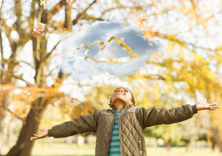 Composition of cloud with house icon over happy african american boy in autumn park. home and family life concept digitally generated image.の写真素材