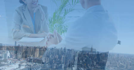 Composition of midsection of businessman and smiling businesswoman in meeting over modern cityscape....