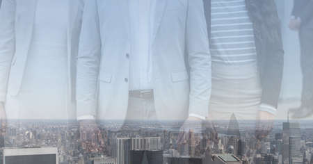 Composition of midsection of male and female business creatives over cityscape. global business,...