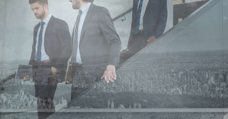 Composition of businessmen walking in modern building. global business travel and finance concept digitally generated image.の写真素材