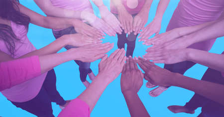 Composition of female friends touching hands in circle on blue background. teamwork, motivation and...