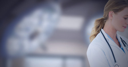 Cropped image of caucasian female doctor against surgical light in background. healthcare and medical professionalism conceptの写真素材