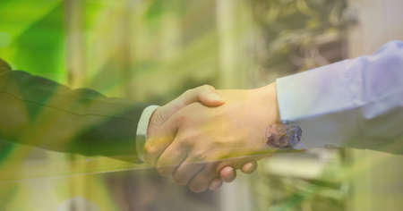 Digital composite image of trees against mid section of two businessmen shaking hands. global...