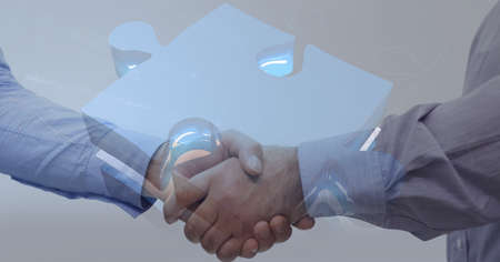 Jigsaw puzzle against mid section of two businessmen shaking hands. global business and technology conceptの写真素材