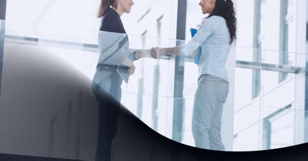 Mid section of two businessmen shaking hands in office against technology background. global business and technology conceptの写真素材