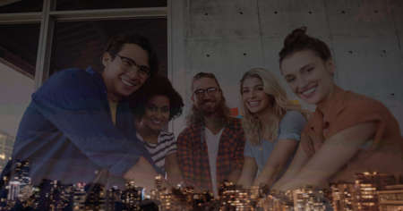 Composition of smiling office colleagues hand stacking over cityscape. teamwork, success, business and finance concept digitally generated image.の写真素材