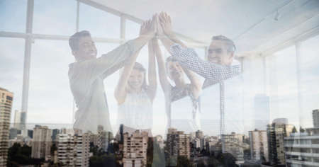 Composition of smiling office colleagues high fiving over cityscape. teamwork, success, business and finance concept digitally generated image.の写真素材