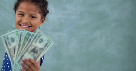 Composition of smiling girl holding american dollar bills on green background. global business, finances and data processing concept digitally generated image.の写真素材