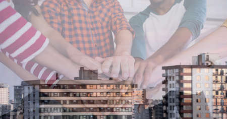Composition of ffice colleagues hand stacking over cityscape. teamwork, success, business and finance concept digitally generated image.の写真素材