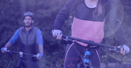 Composition of caucasian man and woman riding bicycles in forest. sport, fitness and active...