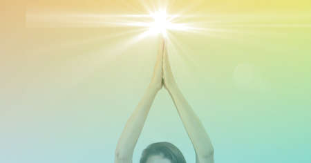Composition of hands of woman practicing yoga with glowing light and yellow to green tint. sport,...
