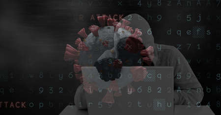 Composition of hooded hacker using laptop with covid cells and cyber attack warning on dark screen....