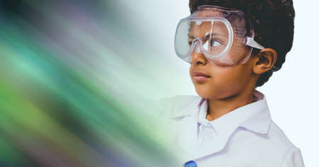 Composition of schoolboy with protective glasses in school laboratory with green motion blur. science, learning and knowledge concept digitally generated image.の写真素材