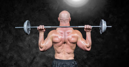 Composition of rear view of muscular man lifting weights with glowing light on black background. sport, fitness and active lifestyle concept digitally generated image.の写真素材