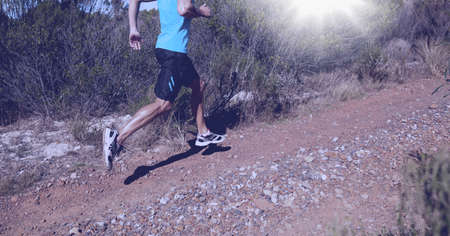 Composition of low section of man running in countryside and glowing light. sport, fitness and...