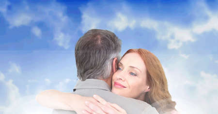 Composition of happy mature couple embracing and smiling, over blue cloudy sky. free time, love and retirement concept digitally generated image.の写真素材