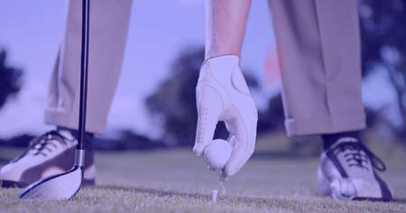 Composition of low section of male golf player with club holding golf ball in golf course. sport, fitness and active lifestyle concept digitally generated image.の写真素材