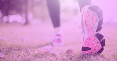 Composition of athletic woman walking in park over pink blur. sport, fitness and active lifestyle concept digitally generated image.の写真素材