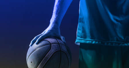 Composition of athletic male basketball player with ball on blue background. sport, fitness and active lifestyle concept digitally generated image.の写真素材