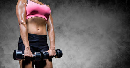 Composition of midsection of strong caucasian woman lifting dumbbells. sport, fitness and active lifestyle concept digitally generated image.の写真素材