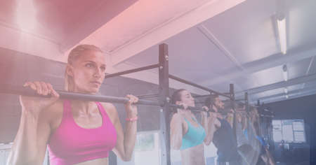 Strong women pulling up on bar exercising in gym with pink tinted background. healthy lifestyle,...