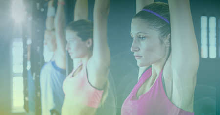 Strong women hanging from bar exercising in gym with blue tinted background. healthy lifestyle, wellbeing and fitness concept digitally generated image.の写真素材