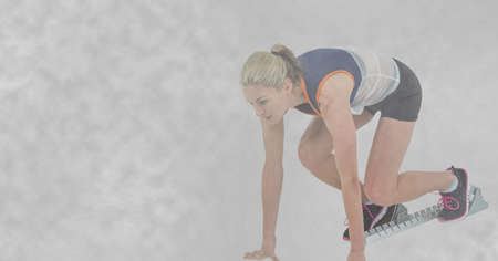 Composition of caucasian female runner in starting blocks and copy space. sport and fitness concept digitally generated image.の写真素材