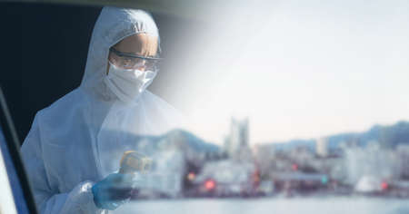 Composition of person wearing ppe suit and mask, with blurred city and copy space. medical services and research during covid 19 pandemic concept digitally generated image.の写真素材