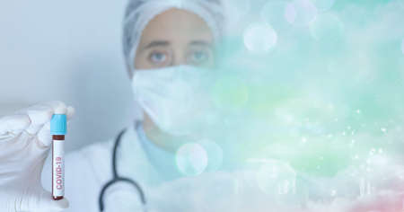 Composition of person in mask and ppe suit holding covid 19 vaccine vial, with blurred copy space. coronavirus, medical and science research concept digitally generated image.の写真素材