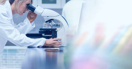 Composition of female lab technician using microscope, with blurred copy space to right. medical and...