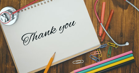 Composition of notebook with thank you note, with stethoscope, stationery and pencils on wooden desk. medical services, research and science concept digitally generated image.の写真素材