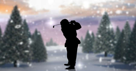 Composition of silhouette of santa claus playing golf over winter landscape. sport and competition concept digitally generated image.の写真素材