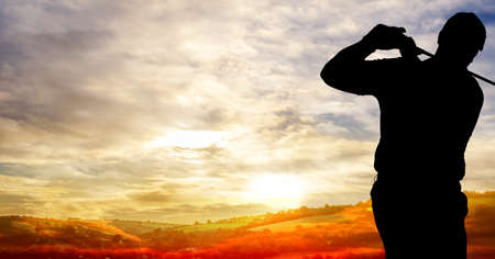 Composition of silhouette of male golf player over landscape and clouds on blue sky with copy space. sport and competition concept digitally generated image.の写真素材