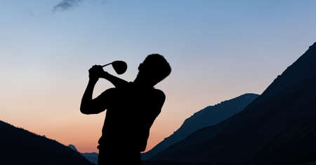Composition of silhouette of male golf player over landscape and blue sky with copy space. sport and...