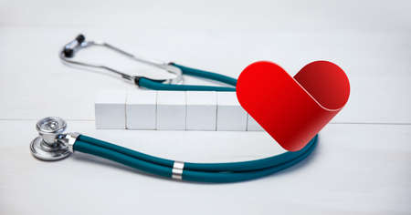 Composition of heart icon over stethoscope and white blocks with copy space on white background. medicine and healthcare concept digitally generated image.の写真素材