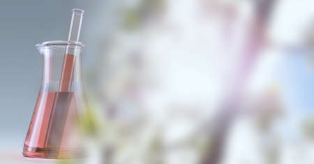Composition of red liquid and stirrer in flask, with blurred pink blossom copy space to right....