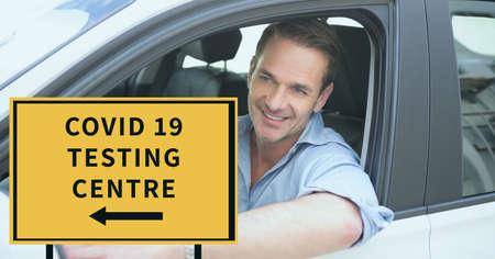 Composition of covid 19 testing centre text on sign over smiling caucasian male driver in car....