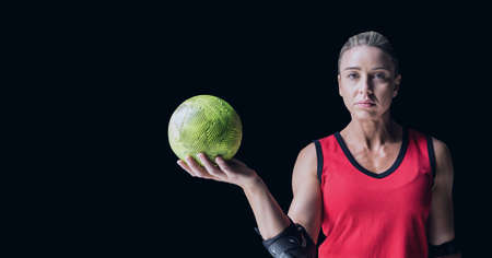 Composition of caucasian female handball player holding ball with copy space on black background....