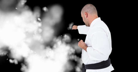 Compostion of caucasian male karate fighter on black background with white blur. championships,...