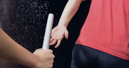 Composition of caucasian male runner passing baton to his teammate on black background....