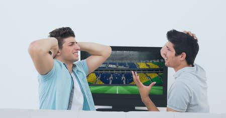 Compostion of two caucasian male friends watching football match on tv on white background. championships, sports and competition concept digitally generated image.の写真素材