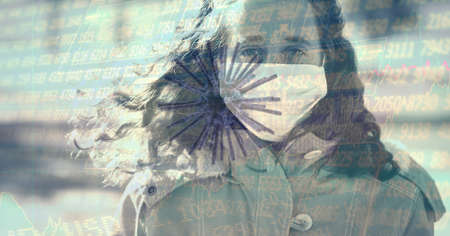 Composition of covid 19 cell and medical data processing over caucasian woman wearing face mask. global covid 19 pandemic and digital interface concept digitally generated image.の写真素材