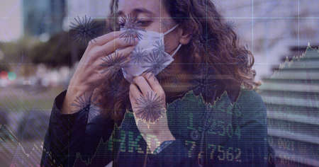 Composition of covid 19 cells and medical data processing over caucasian woman wearing face mask. global covid 19 pandemic and digital interface concept digitally generated image.の写真素材