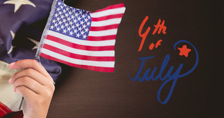 Happy independence day text and hand holding a american flag against us flag on wooden background. american patriotism and independence day celebration conceptの写真素材